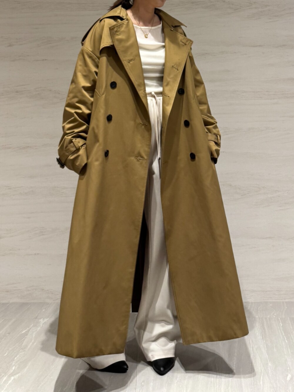 ホワイト系のTシャツ/カットソー、ホワイト系のスラックス、イエロー系のトレンチコートを着用したレディースの冬コーディネートの4枚目の写真