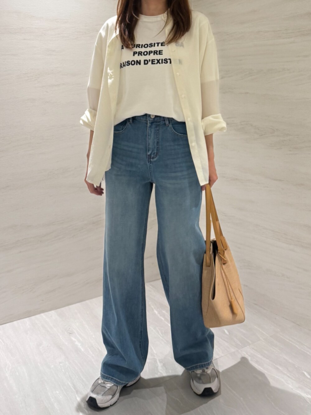 ベージュ系のトートバッグ、ブルー系のデニムパンツ、ホワイト系のシャツ/ブラウスを着用したレディースの夏コーディネートの3枚目の写真