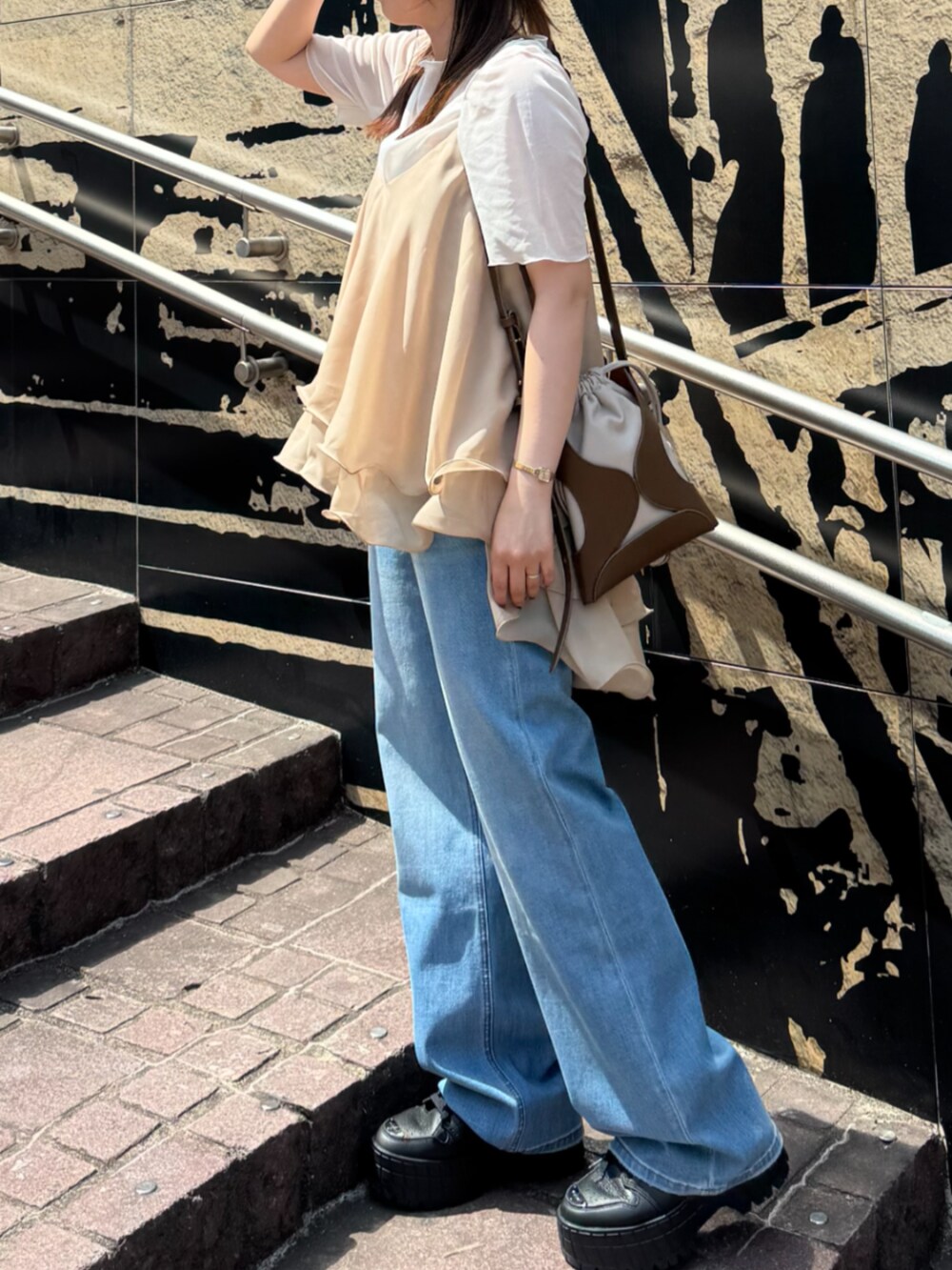 イエロー系のショルダーバッグ、ブルー系のデニムパンツ、ベージュ系のキャミソールを着用したレディースの夏コーディネートの4枚目の写真