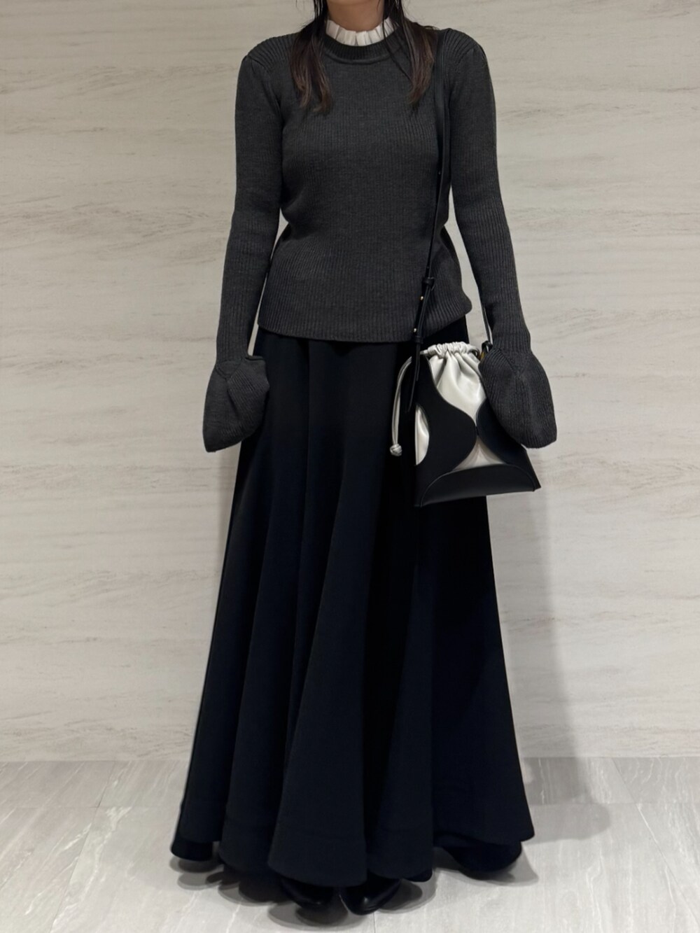 ブラック系のスカート、グレー系のニット/セーター、ブラック系のショルダーバッグを着用したレディースの秋コーディネートの2枚目の写真