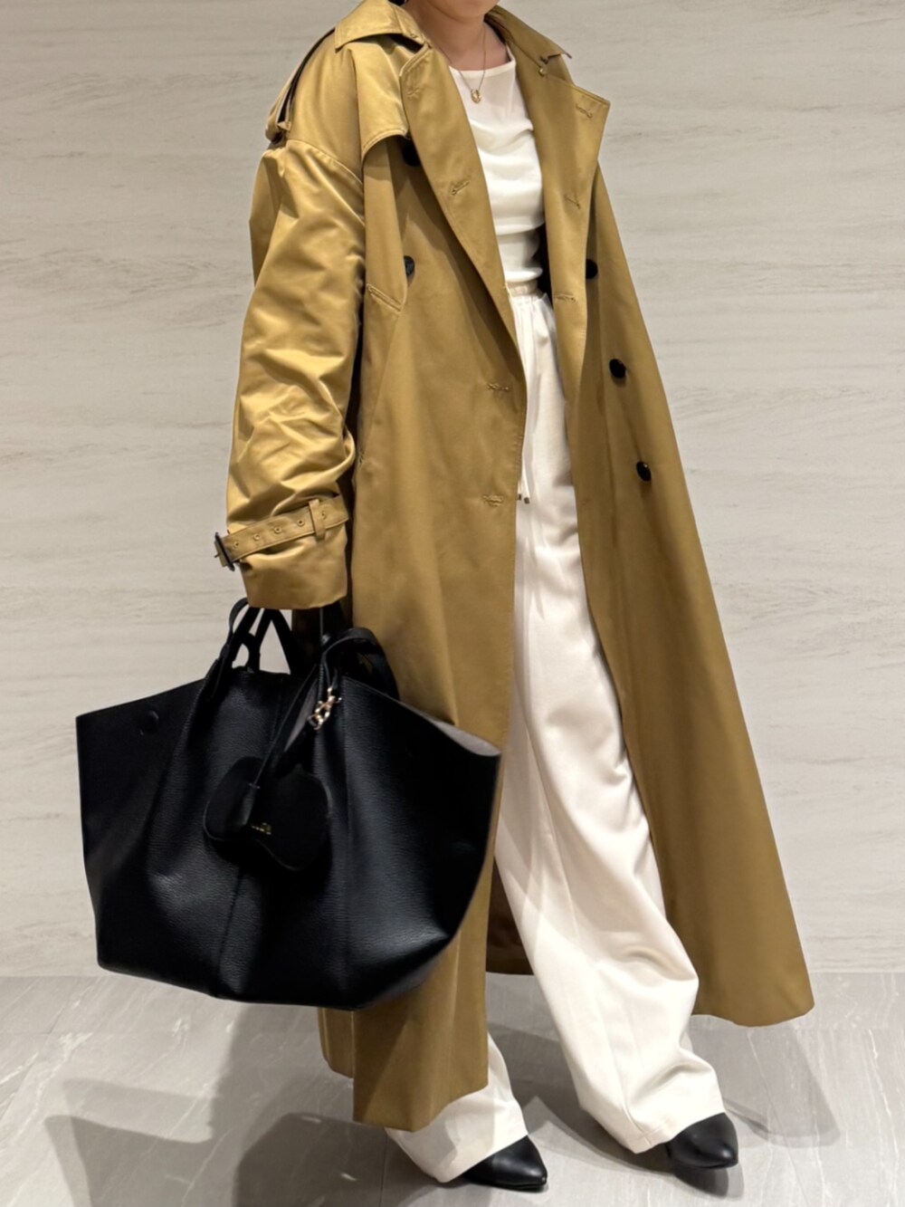 ホワイト系のTシャツ/カットソー、ホワイト系のスラックス、イエロー系のトレンチコートを着用したレディースの冬コーディネートの7枚目の写真