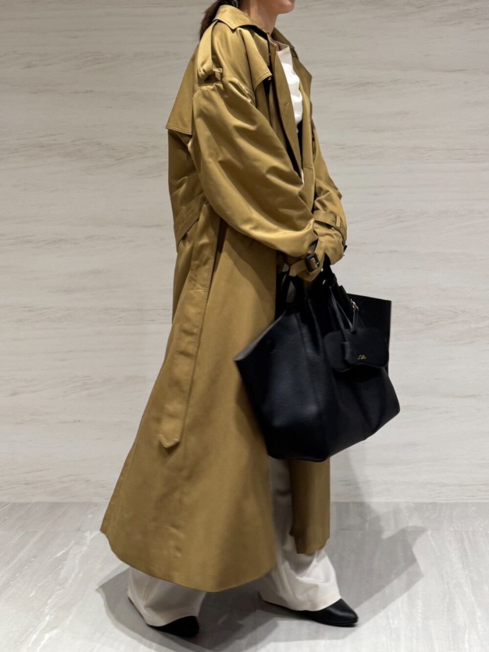 ホワイト系のTシャツ/カットソー、ホワイト系のスラックス、イエロー系のトレンチコートを着用したレディースの冬コーディネートの6枚目の写真