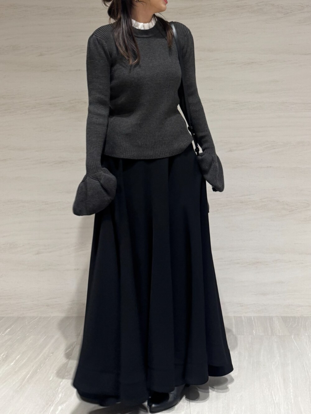 ブラック系のスカート、グレー系のニット/セーター、ブラック系のショルダーバッグを着用したレディースの秋コーディネートの5枚目の写真