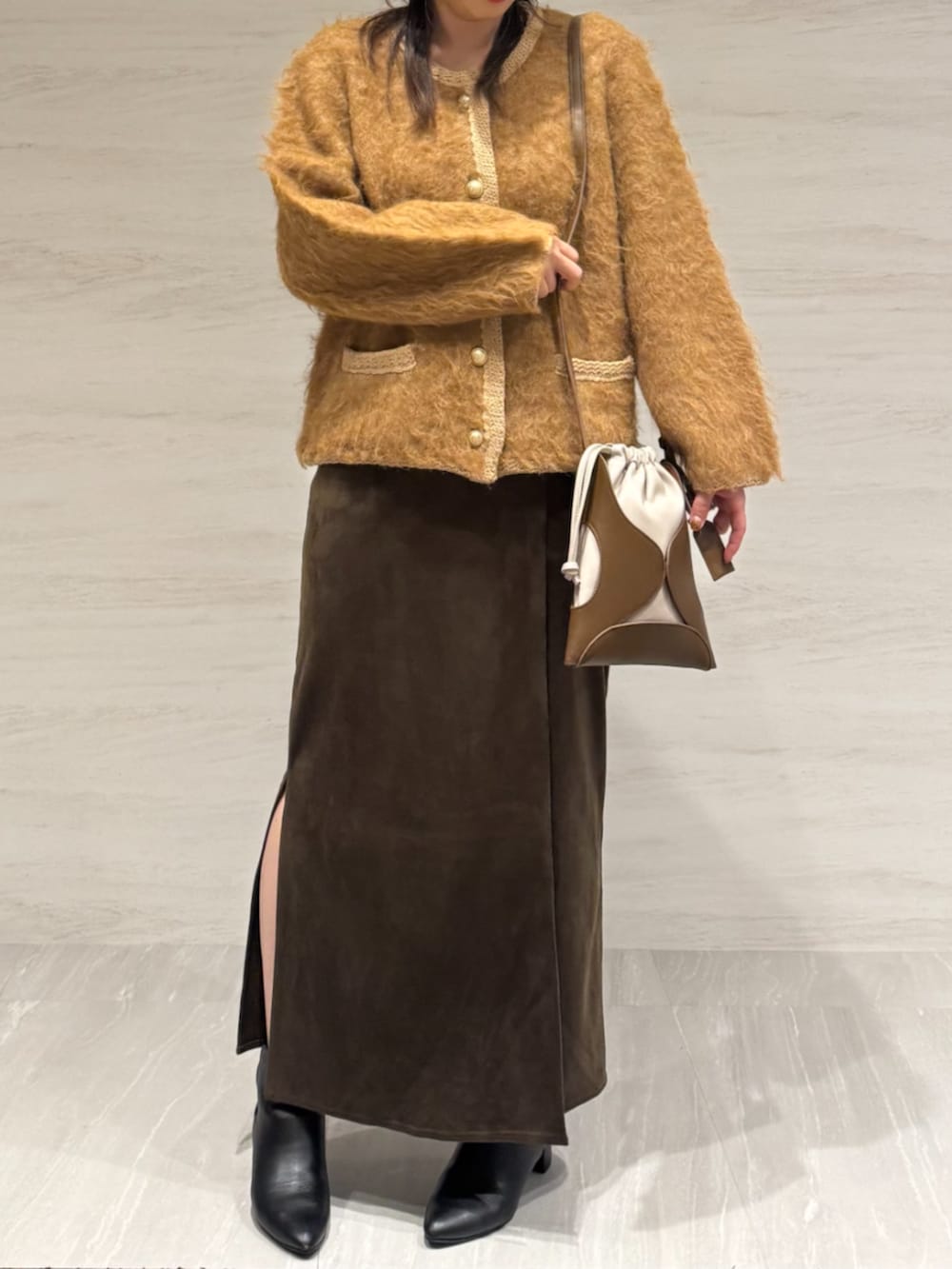ブラウン系のスカート、イエロー系のショルダーバッグ、イエロー系のカーディガン/ボレロを着用したレディースの冬コーディネートの2枚目の写真