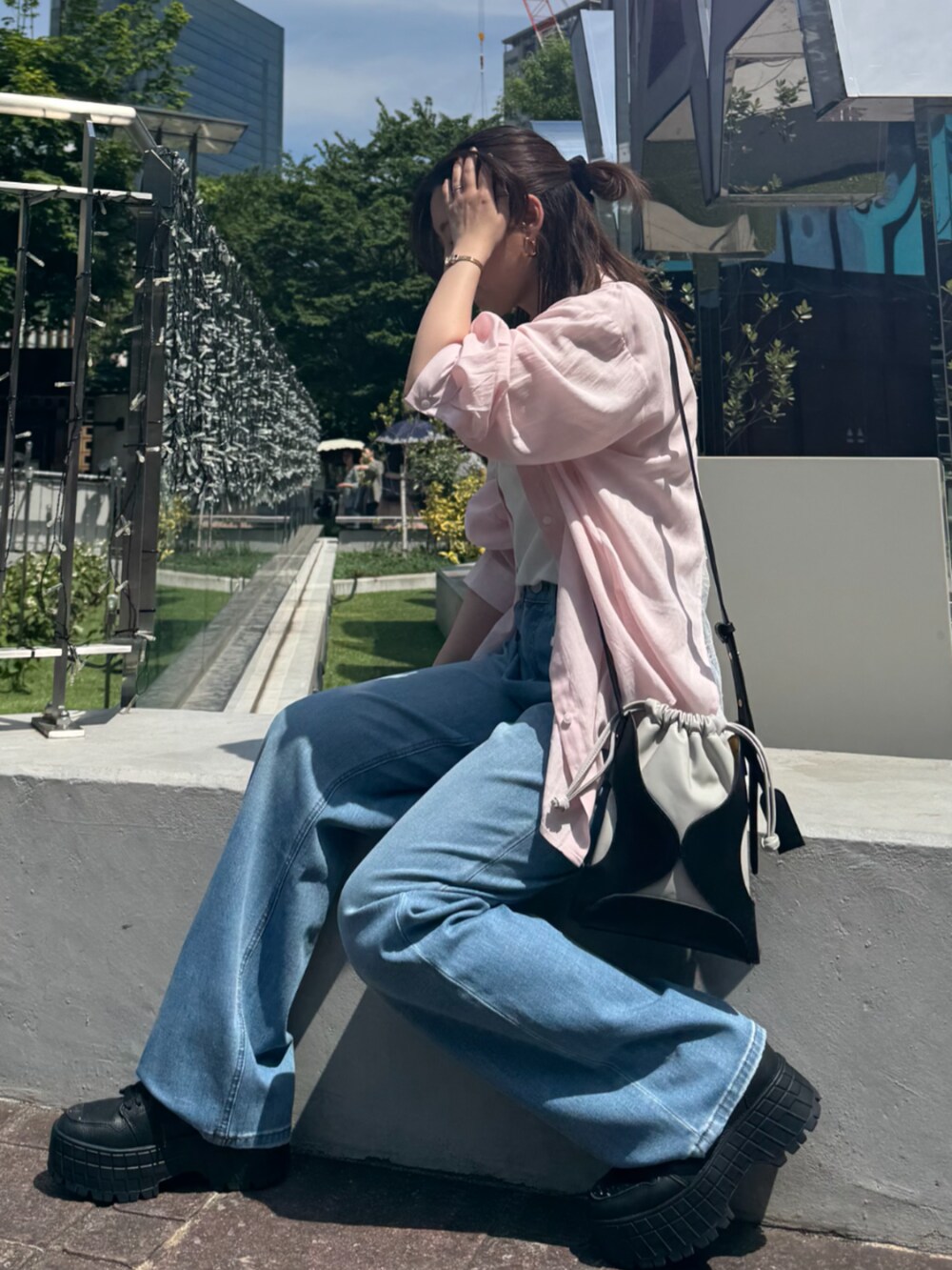 ブラック系のショルダーバッグ、ブルー系のデニムパンツ、ピンク系のシャツ/ブラウスを着用したレディースの夏コーディネートの2枚目の写真