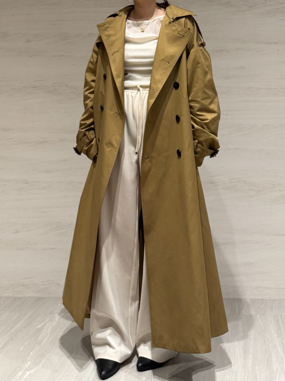 ホワイト系のTシャツ/カットソー、ホワイト系のスラックス、イエロー系のトレンチコートを着用したレディースの冬コーディネートの2枚目の写真