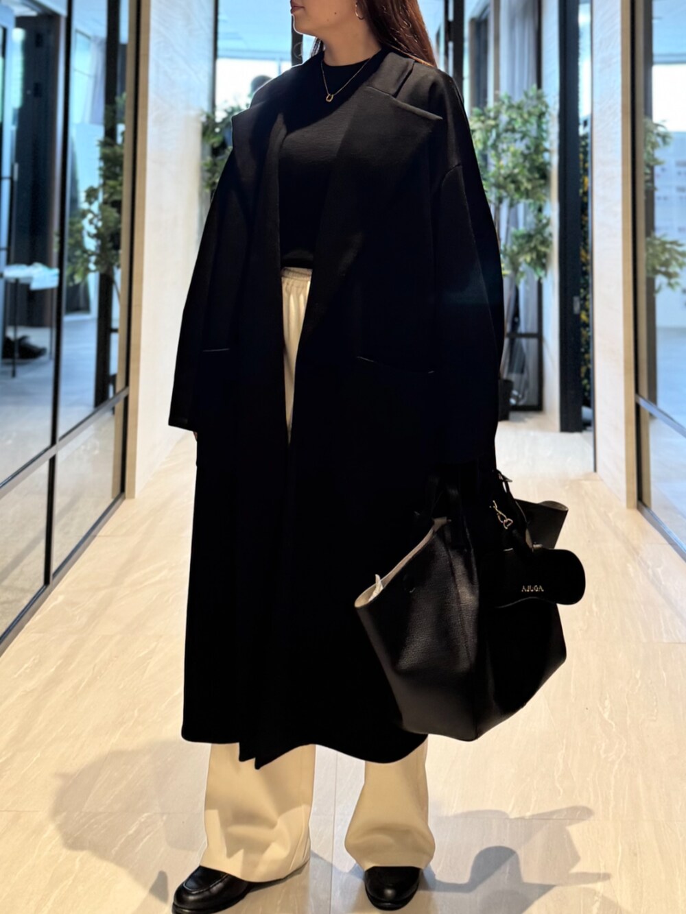 ブラック系のトートバッグ、ブラック系のニット/セーター、ブラック系のチェスターコートを着用したレディースの秋コーディネートの4枚目の写真