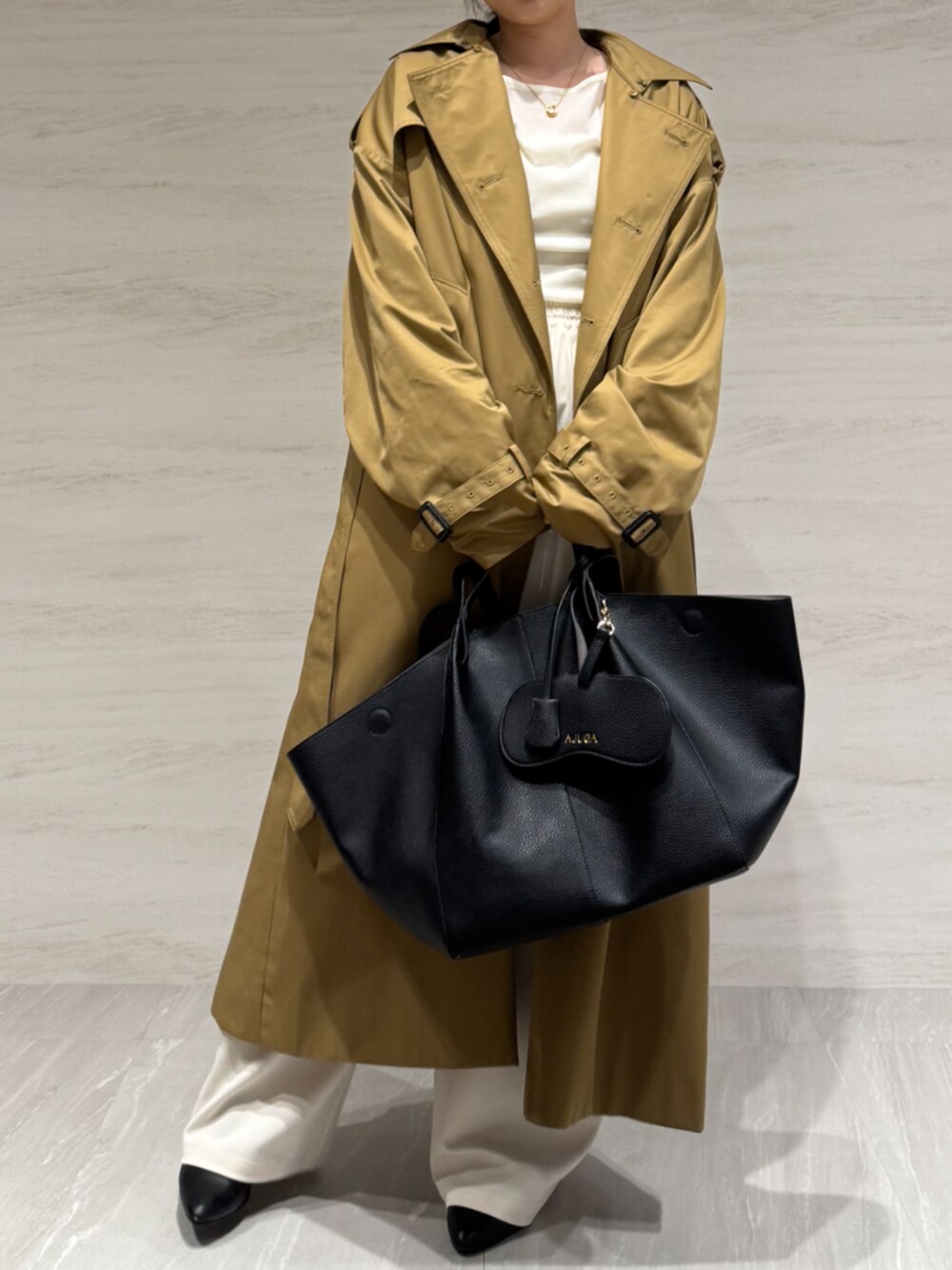 ホワイト系のTシャツ/カットソー、ホワイト系のスラックス、イエロー系のトレンチコートを着用したレディースの冬コーディネートの8枚目の写真