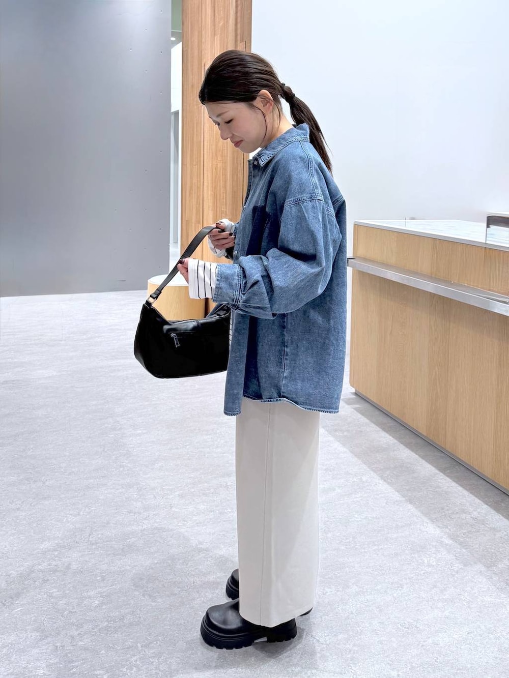 グレー系のスカート、ブルー系のシャツ/ブラウス、ブラック系のショルダーバッグを着用したレディースの冬コーディネートの4枚目の写真