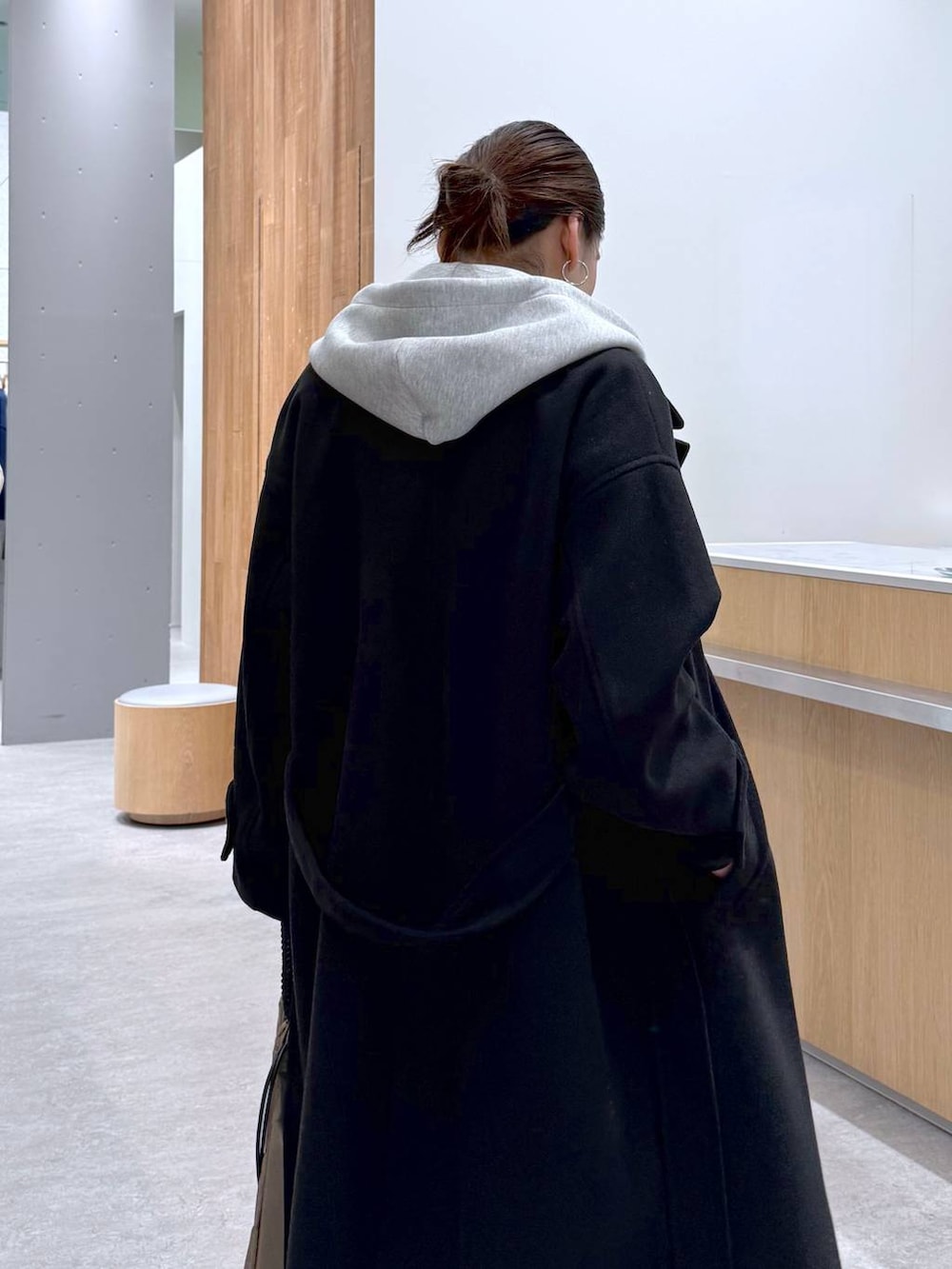 ブラック系のステンカラーコート、グレー系のスウェットパンツ、グレー系のベストを着用したレディースの秋コーディネートの7枚目の写真