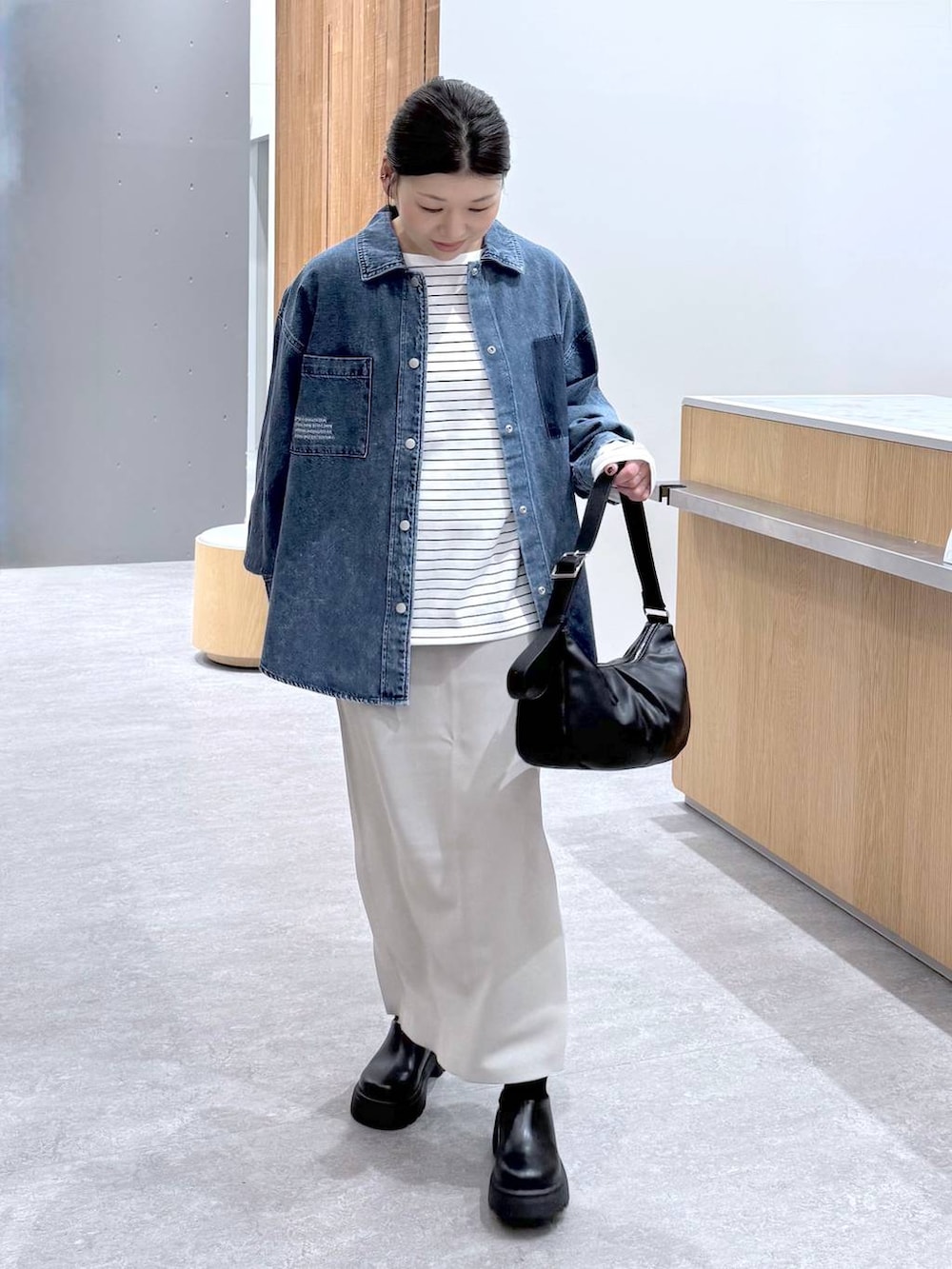 グレー系のスカート、ブルー系のシャツ/ブラウス、ブラック系のショルダーバッグを着用したレディースの冬コーディネートの2枚目の写真