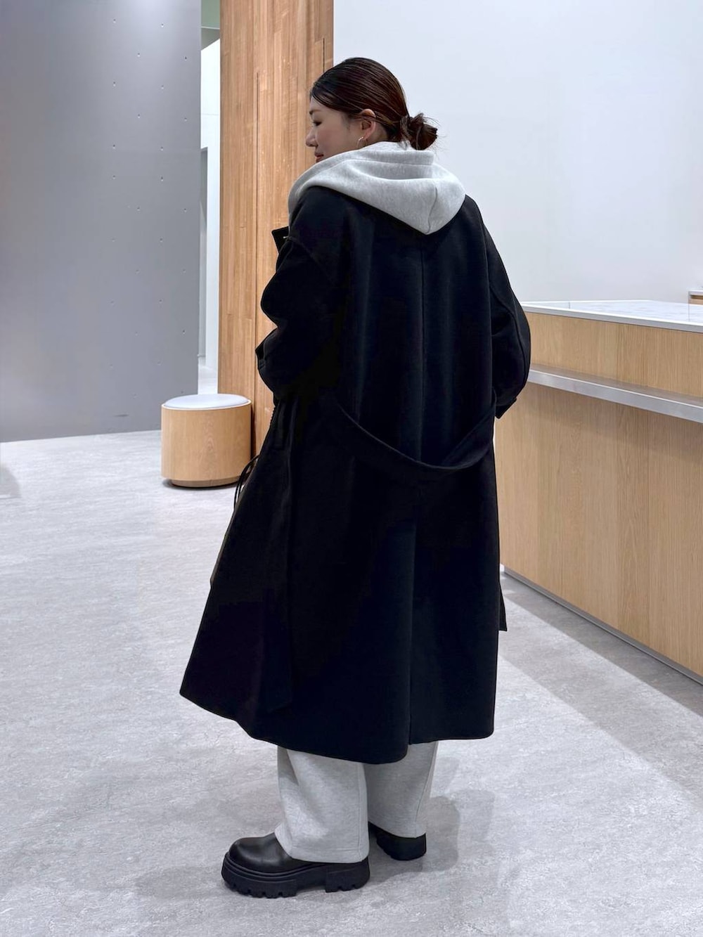 ブラック系のステンカラーコート、グレー系のスウェットパンツ、グレー系のベストを着用したレディースの秋コーディネートの8枚目の写真