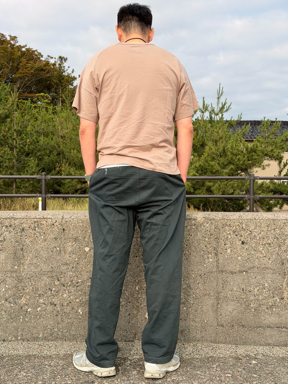 ベージュ系のTシャツ/カットソー、ブラック系のチノパンツ、グレー系のスニーカーを着用したメンズの夏コーディネートの2枚目の写真