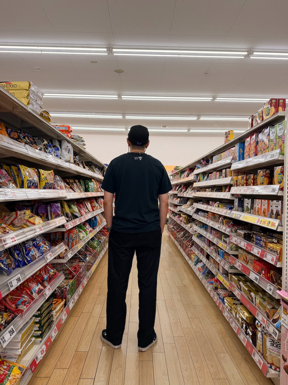 ブラック系のTシャツ/カットソー、ブラック系のチノパンツ、ブラック系のスニーカーを着用したメンズの夏コーディネートの2枚目の写真