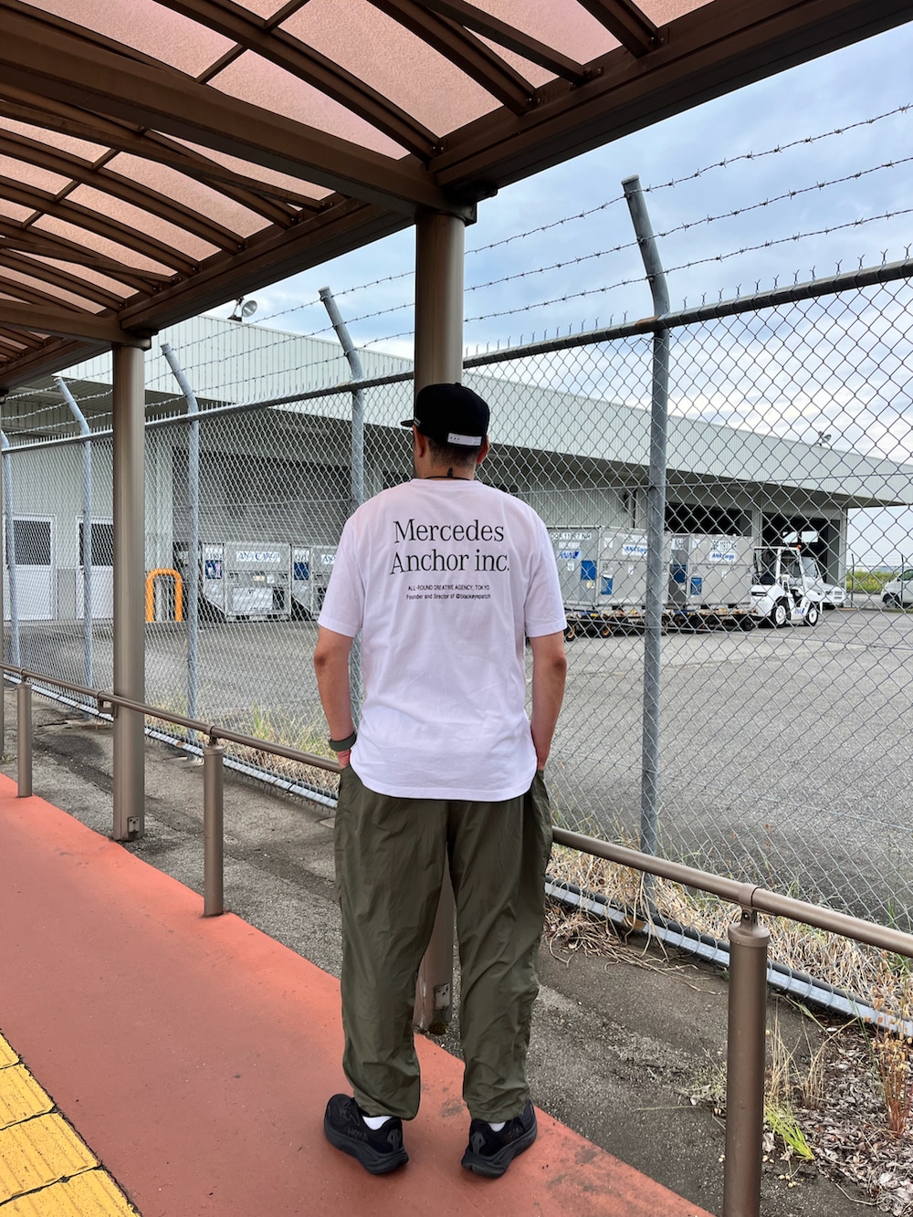 ホワイト系のTシャツ/カットソー、グリーン系のカーゴパンツ、ブラック系のスニーカーを着用したメンズの春コーディネートの2枚目の写真