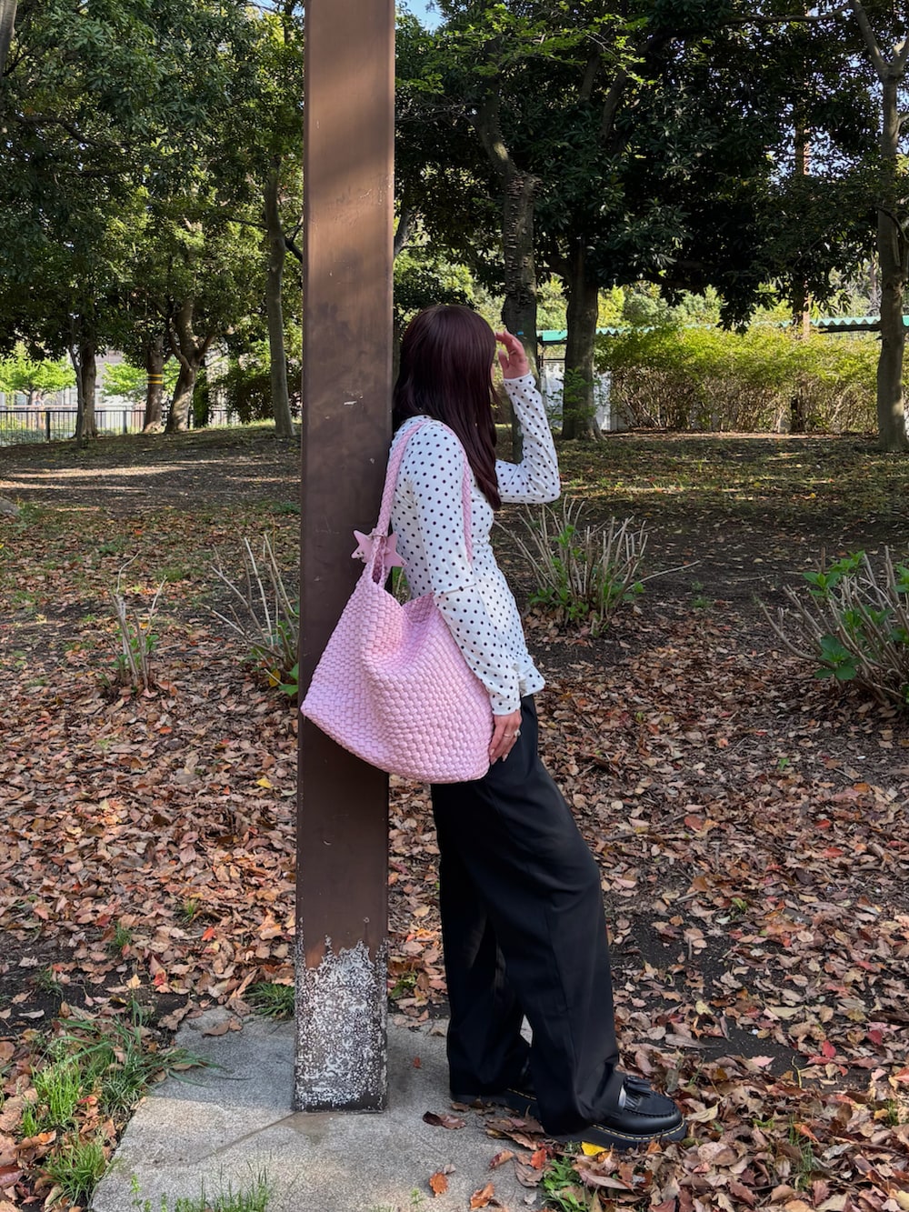 ホワイト系のトップス、ブラック系のニット/セーター、ブラック系のショルダーバッグを着用したレディースの春コーディネートの4枚目の写真