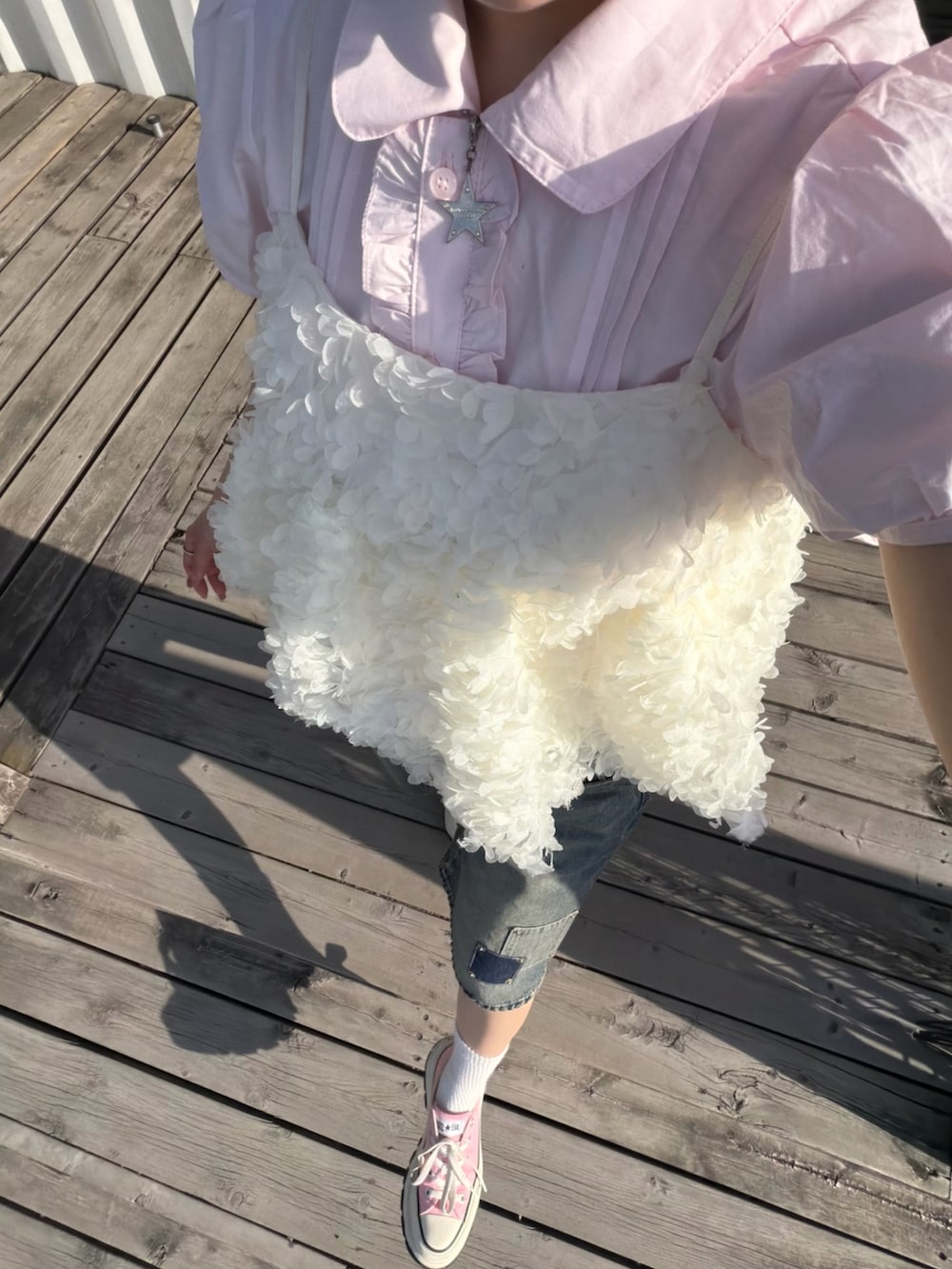 ピンク系のトップス、ホワイト系のワンピース/ドレス、ブルー系のデニムパンツを着用したレディースの春コーディネートの2枚目の写真