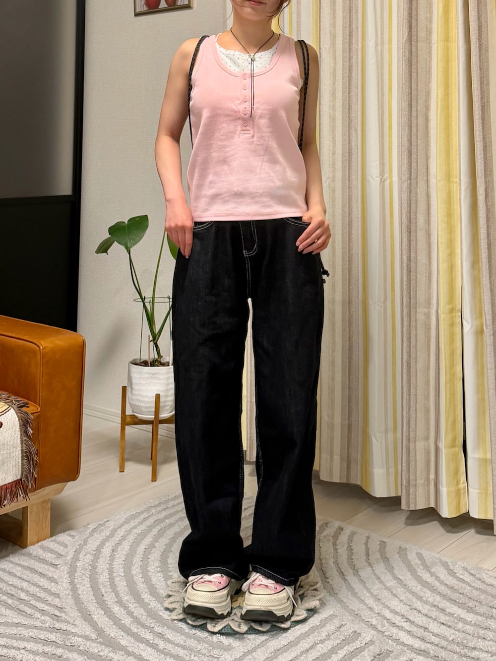 ピンク系のタンクトップ、ブラック系のデニムパンツ、ピンク系のスニーカーを着用したレディースの春コーディネートの3枚目の写真