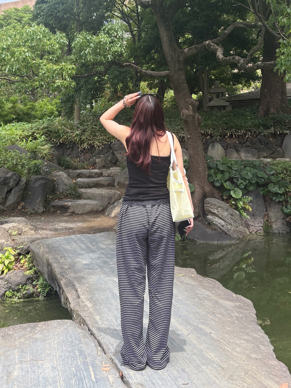 ブラック系のスウェットパンツ、イエロー系のトートバッグ、ブラック系のサンダルを着用したレディースの夏コーディネートの3枚目の写真