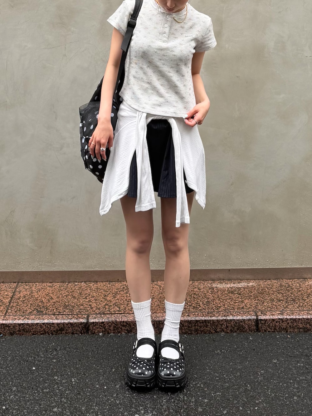 ホワイト系のトップス、ブラック系のバッグ、グレー系のトップスを着用したレディースの夏コーディネートの2枚目の写真