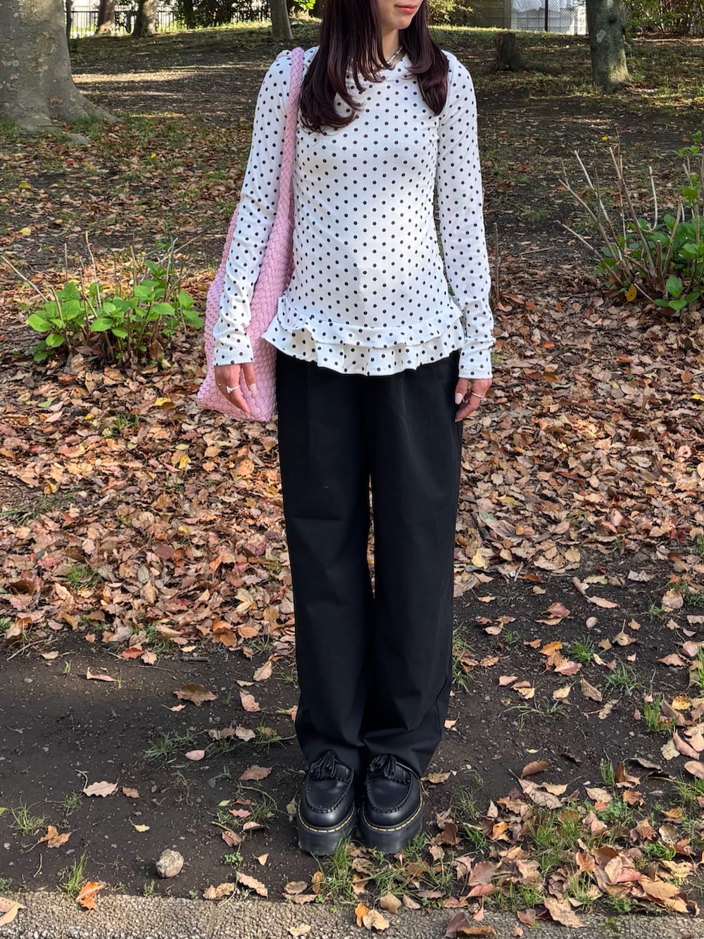 ホワイト系のトップス、ブラック系のニット/セーター、ブラック系のショルダーバッグを着用したレディースの春コーディネートの3枚目の写真