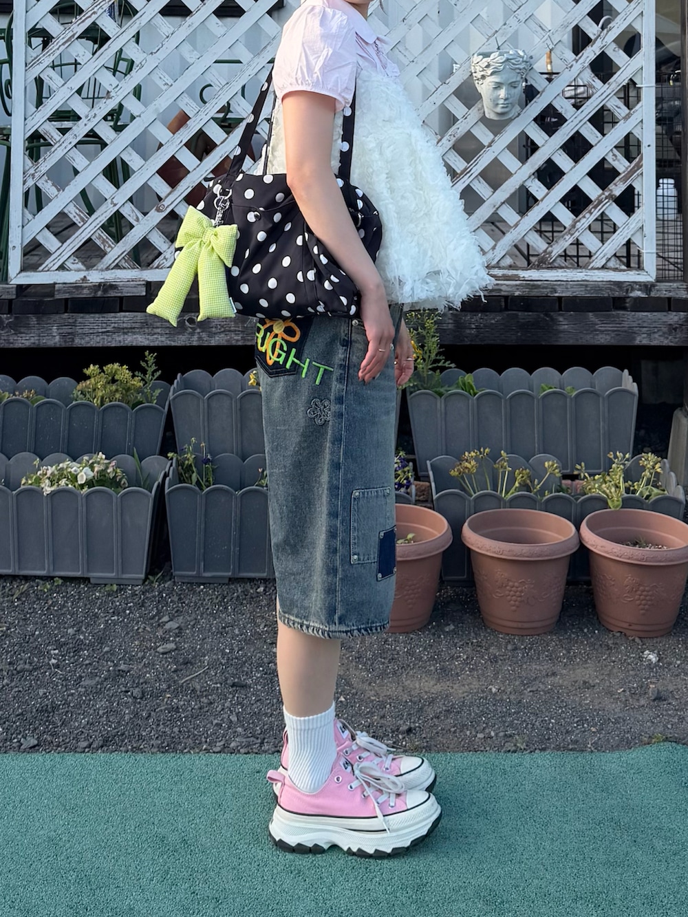 ピンク系のトップス、ホワイト系のワンピース/ドレス、ブルー系のデニムパンツを着用したレディースの春コーディネートの3枚目の写真