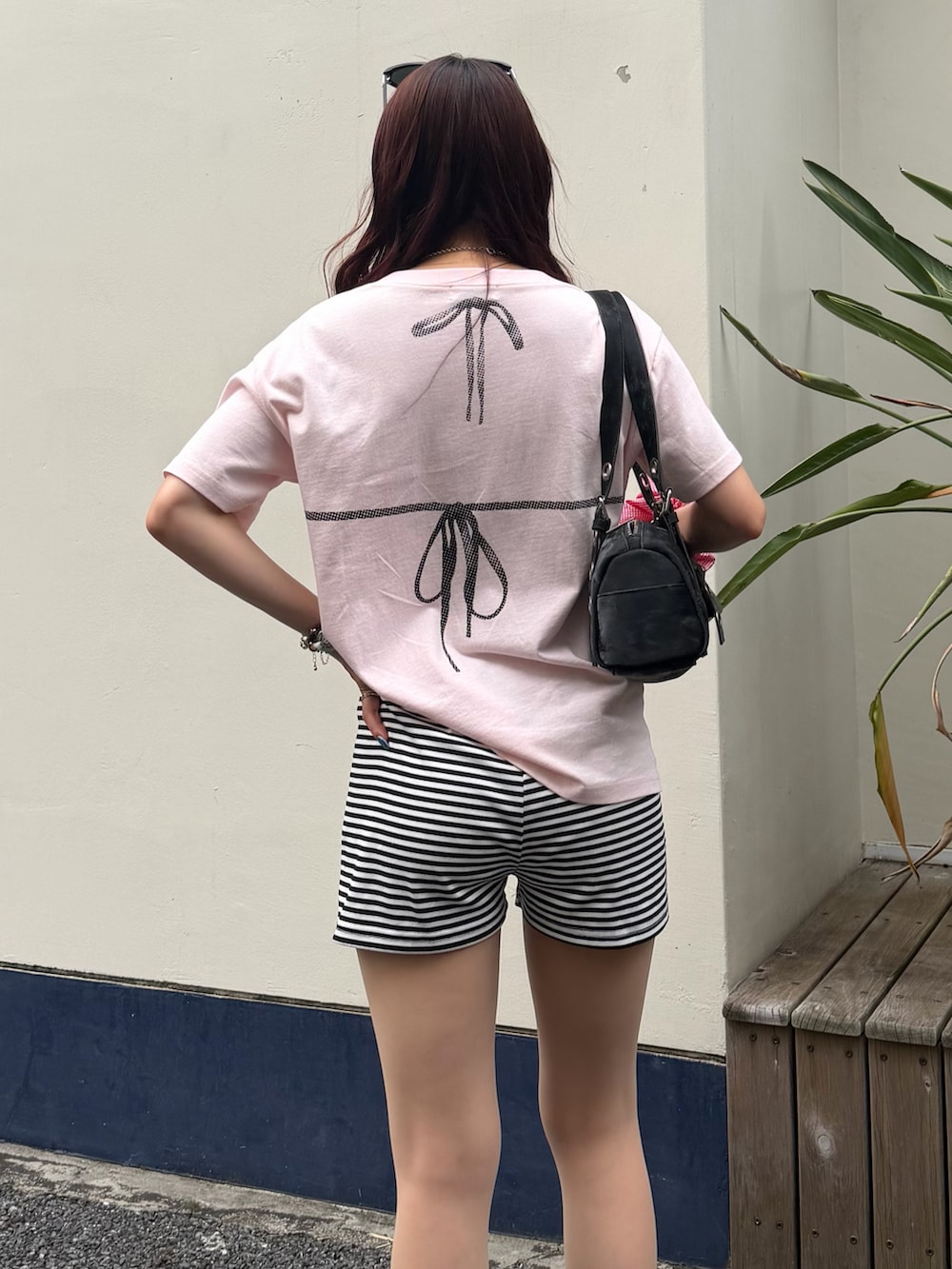 ピンク系のTシャツ/カットソー、ブラック系のショルダーバッグ、ホワイト系のパンツを着用したレディースの夏コーディネートの2枚目の写真