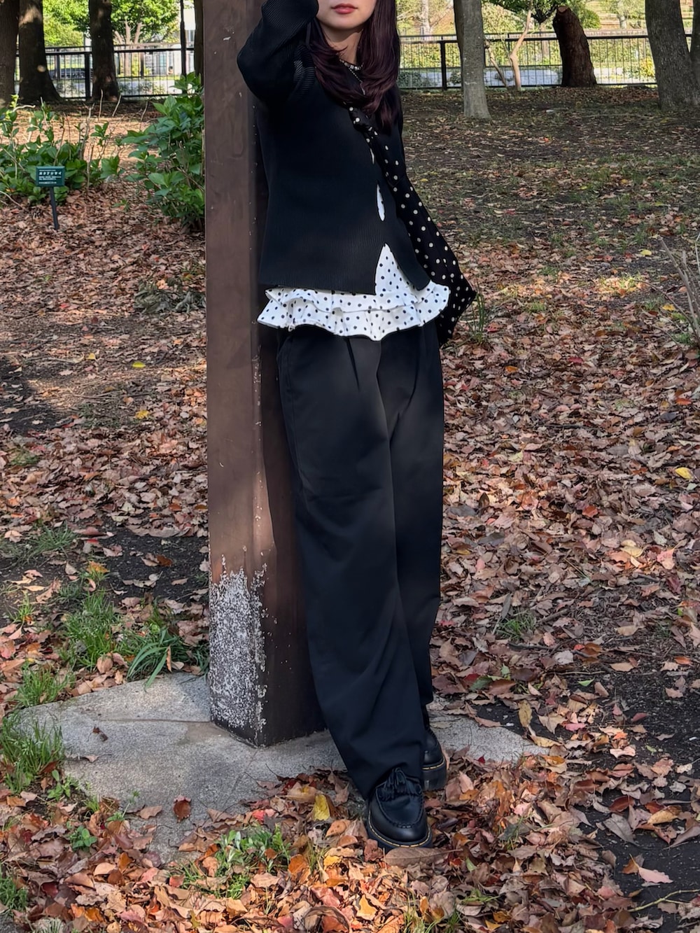 ホワイト系のトップス、ブラック系のニット/セーター、ブラック系のショルダーバッグを着用したレディースの春コーディネートの5枚目の写真