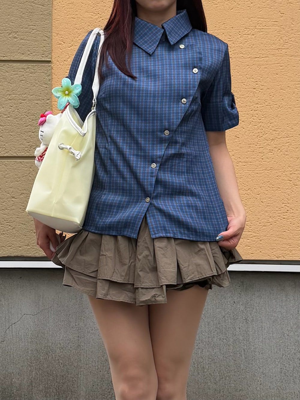 イエロー系のトートバッグ、グリーン系のスカート、ブラウン系のブーツを着用したレディースの夏コーディネートの2枚目の写真
