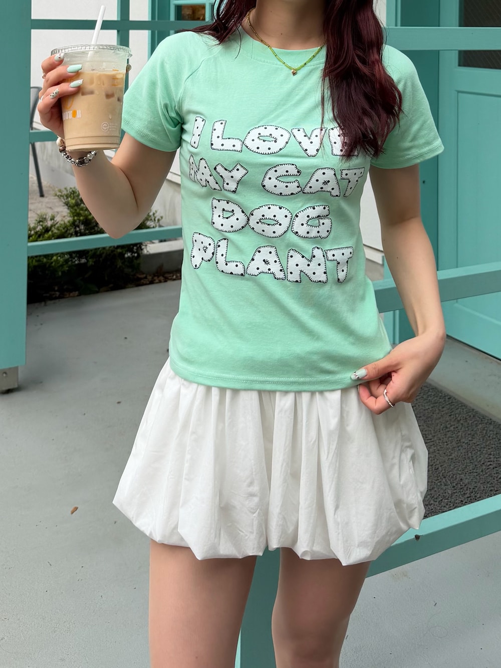 ホワイト系のスカート、グリーン系のバッグ、グリーン系のTシャツ/カットソーを着用したレディースの夏コーディネートの2枚目の写真