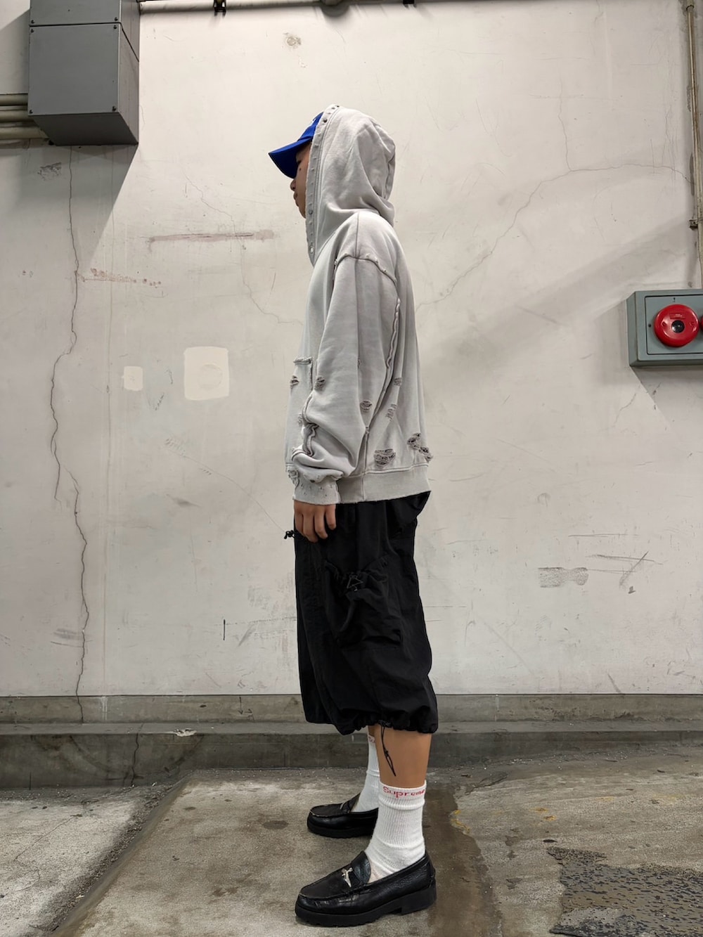 ホワイト系のパーカー、ブラック系のパンツ、ブルー系のキャップを着用したメンズの夏コーディネートの2枚目の写真