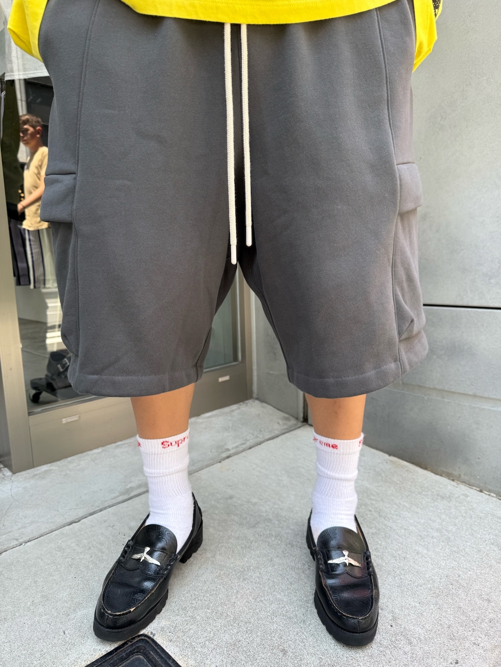 イエロー系のTシャツ/カットソー、グレー系のカーゴパンツ、ブラック系のローファーを着用したメンズの夏コーディネートの5枚目の写真