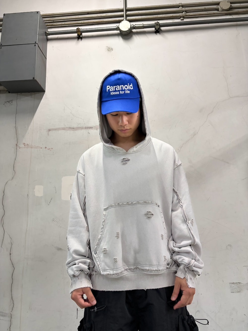 ホワイト系のパーカー、ブラック系のパンツ、ブルー系のキャップを着用したメンズの夏コーディネートの5枚目の写真