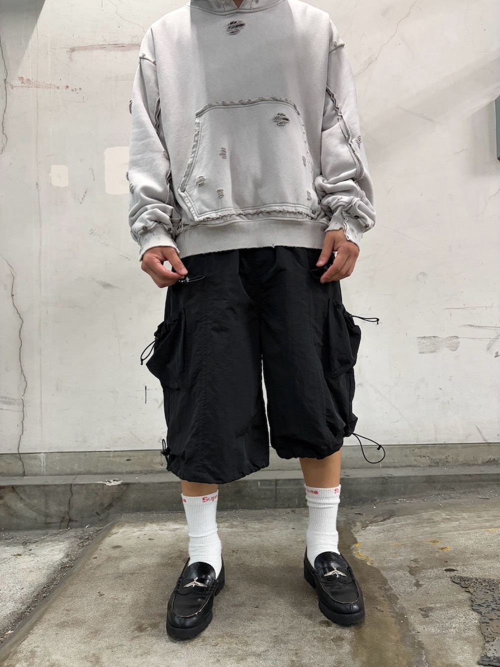 ホワイト系のパーカー、ブラック系のパンツ、ブルー系のキャップを着用したメンズの夏コーディネートの6枚目の写真