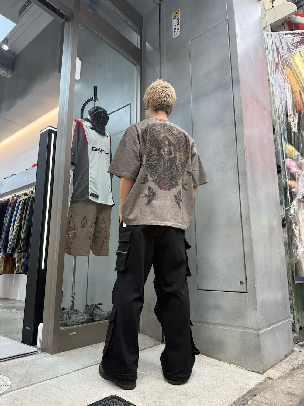 ブラック系のカーゴパンツ、ベージュ系のTシャツ/カットソーを着用したメンズの夏コーディネートの3枚目の写真