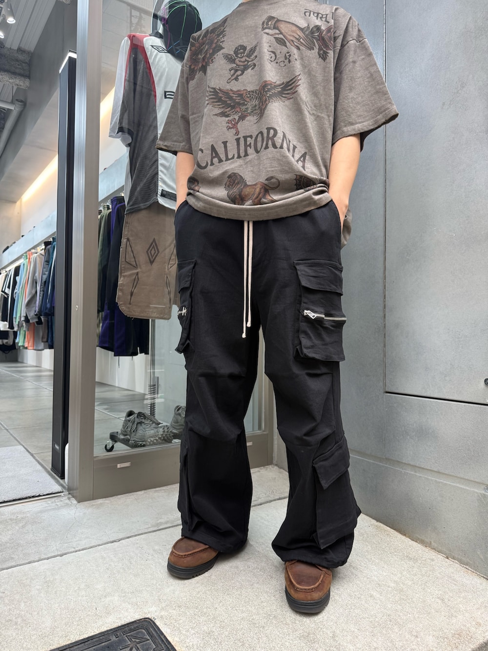 ブラック系のカーゴパンツ、ベージュ系のTシャツ/カットソーを着用したメンズの夏コーディネートの5枚目の写真