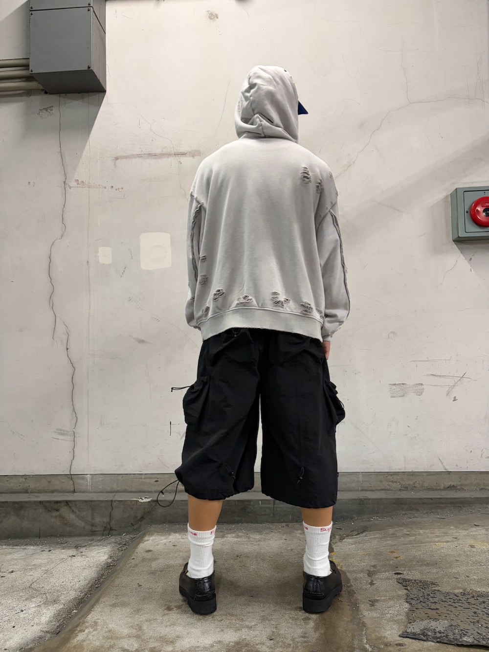 ホワイト系のパーカー、ブラック系のパンツ、ブルー系のキャップを着用したメンズの夏コーディネートの3枚目の写真