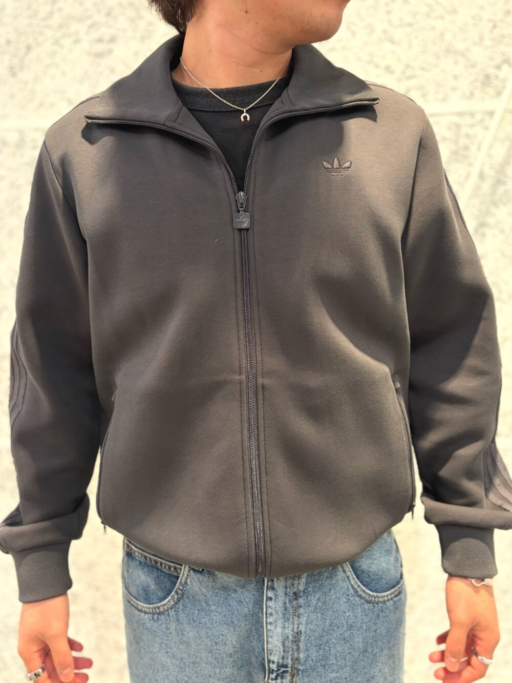 ブルー系のデニムパンツ、ブラック系のトップス、グレー系のスニーカーを着用したメンズの秋コーディネートの3枚目の写真