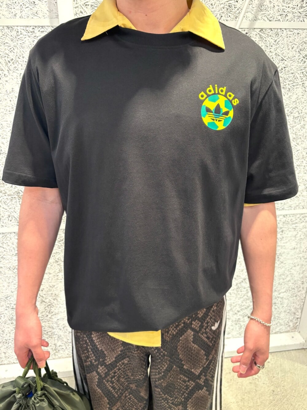 ブラック系のTシャツ/カットソー、ブラウン系のデニムパンツ、グリーン系のバッグを着用したメンズの夏コーディネートの3枚目の写真