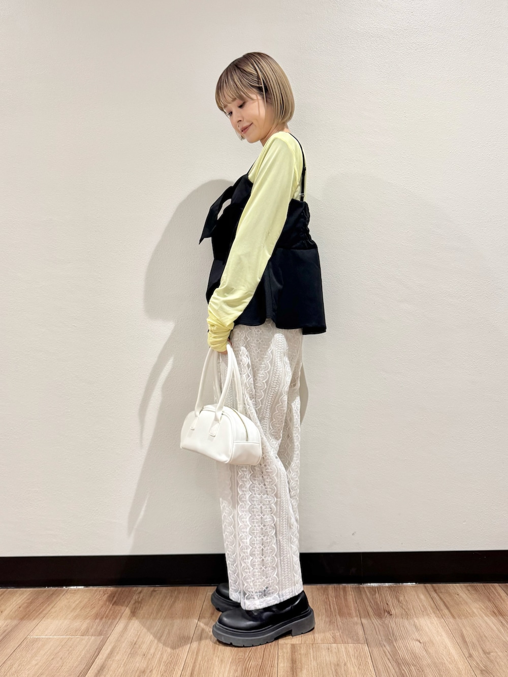 イエロー系のTシャツ/カットソー、ブラック系のベスト、ホワイト系のその他パンツを着用したレディースの春コーディネートの3枚目の写真
