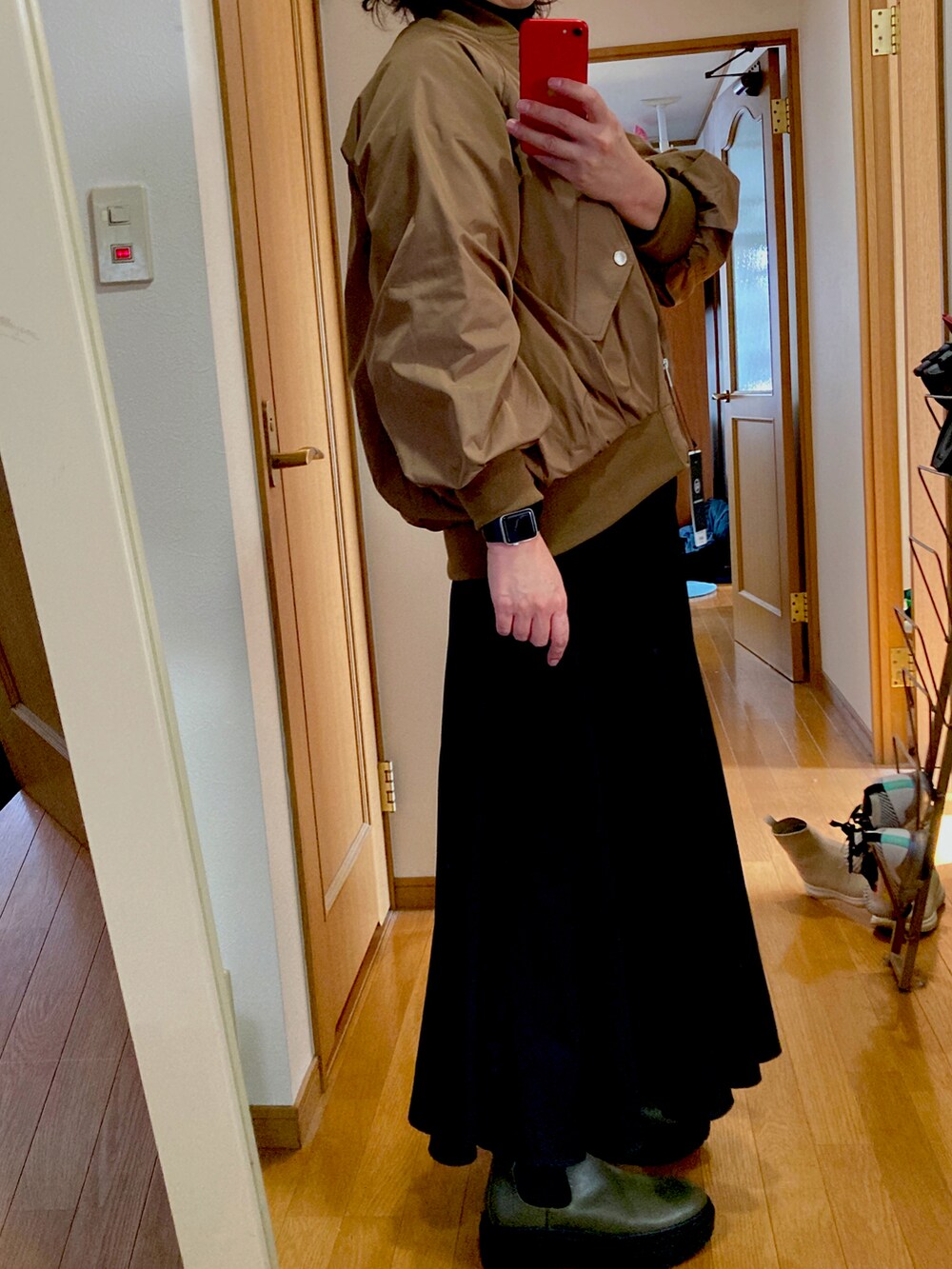 グリーン系のブーツ、ブラック系のスカート、ブラック系のニット/セーターを着用したレディースの秋コーディネートの2枚目の写真