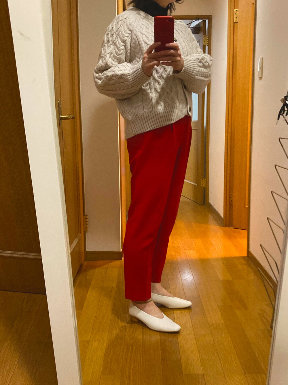 レッド系のパンツ、ホワイト系のニット/セーター、ホワイト系のパンプスを着用したレディースの冬コーディネートの2枚目の写真