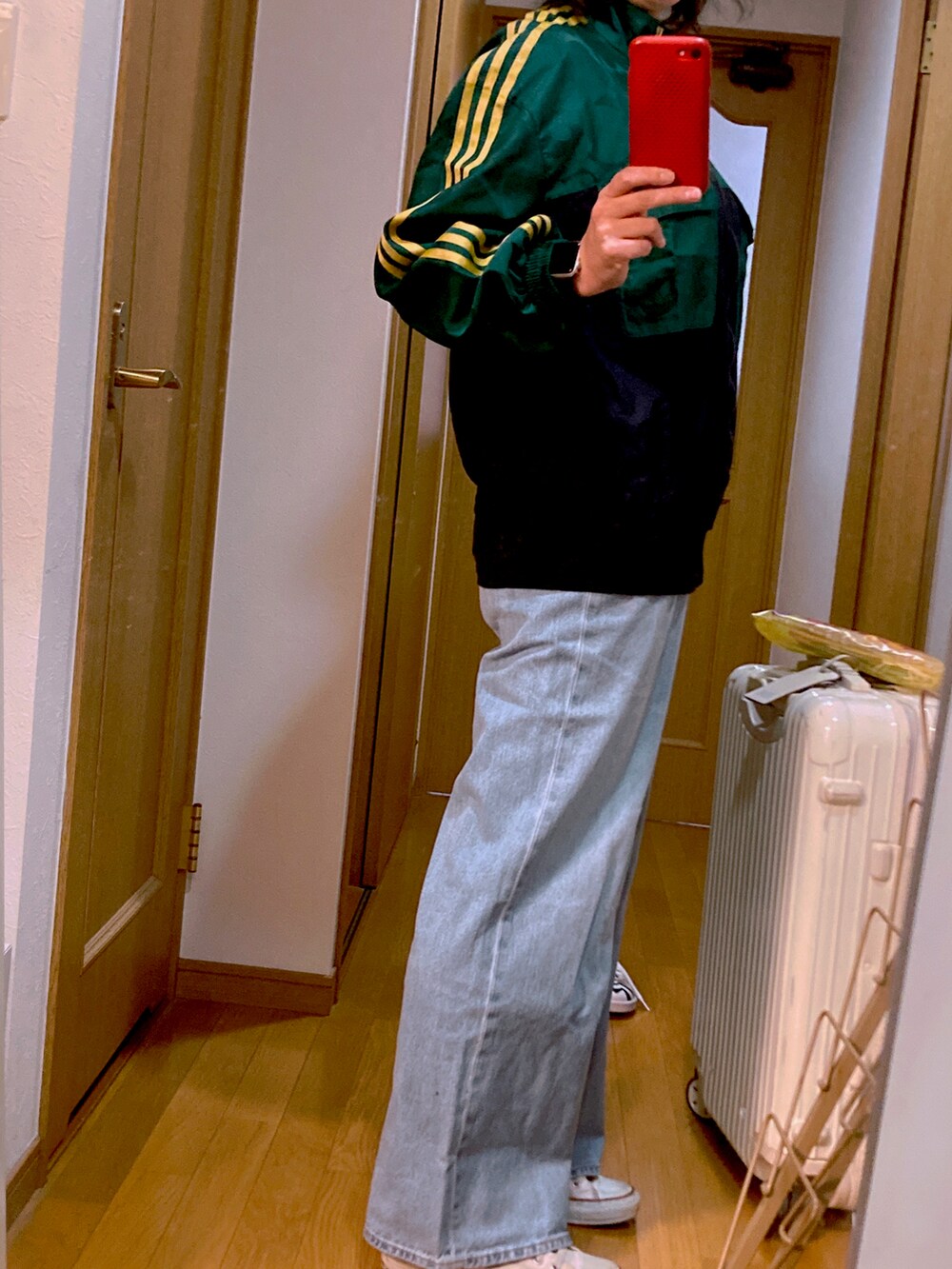 ブルー系のデニムパンツ、グリーン系のジャージ、ホワイト系のスニーカーを着用したレディースの冬コーディネートの2枚目の写真