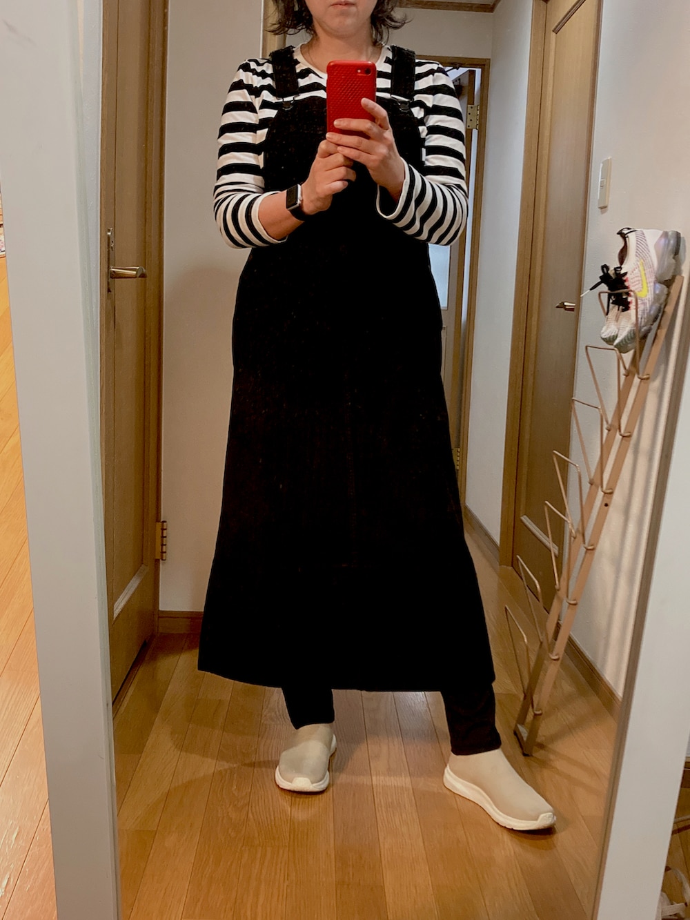 ブラック系のジャンパースカート、ベージュ系のスニーカー、ブラウン系のカーディガン/ボレロを着用したレディースの秋コーディネートの2枚目の写真