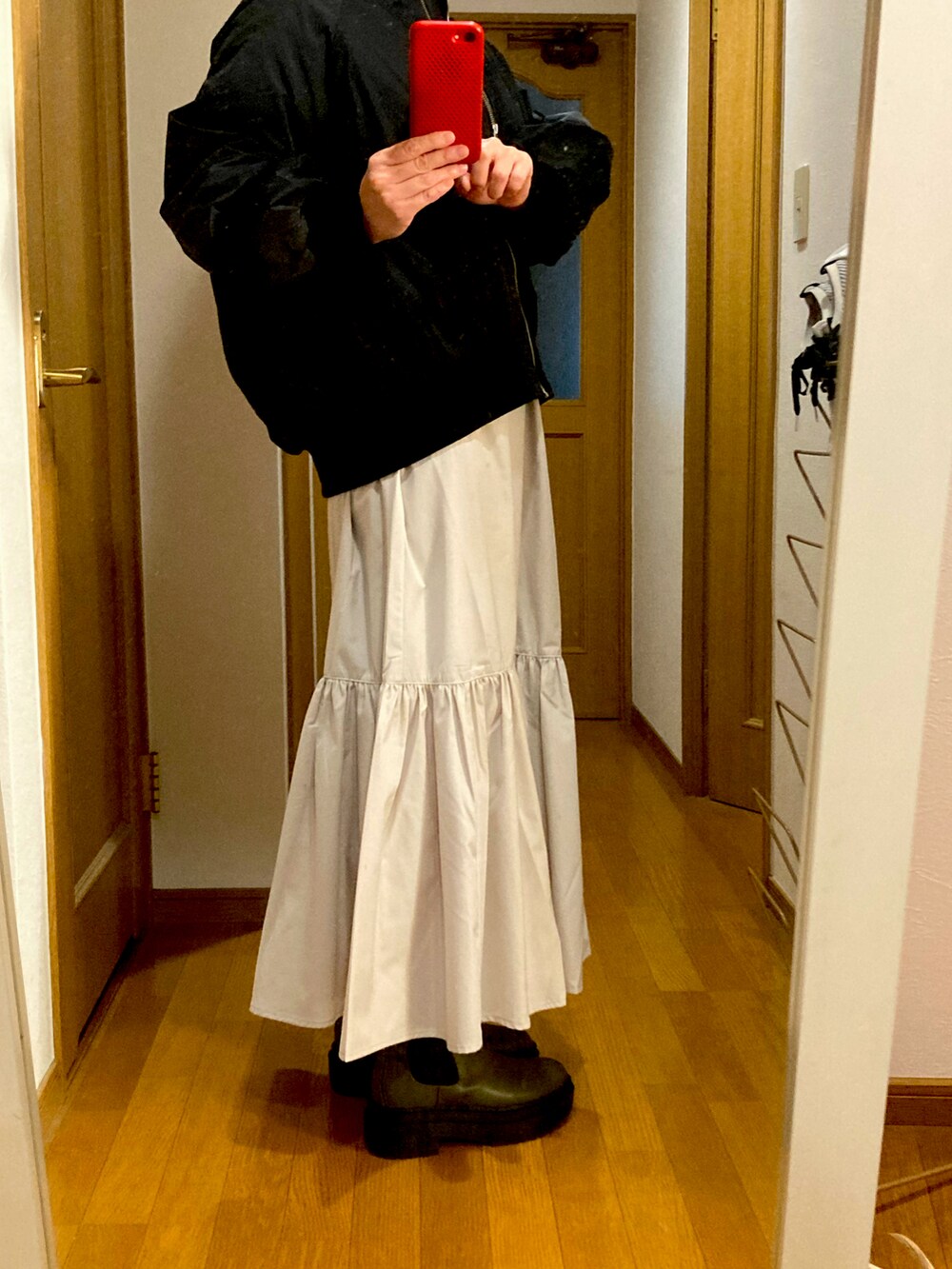 ブラック系のMA-1、ホワイト系のスカート、グリーン系のブーツを着用したレディースの冬コーディネートの2枚目の写真