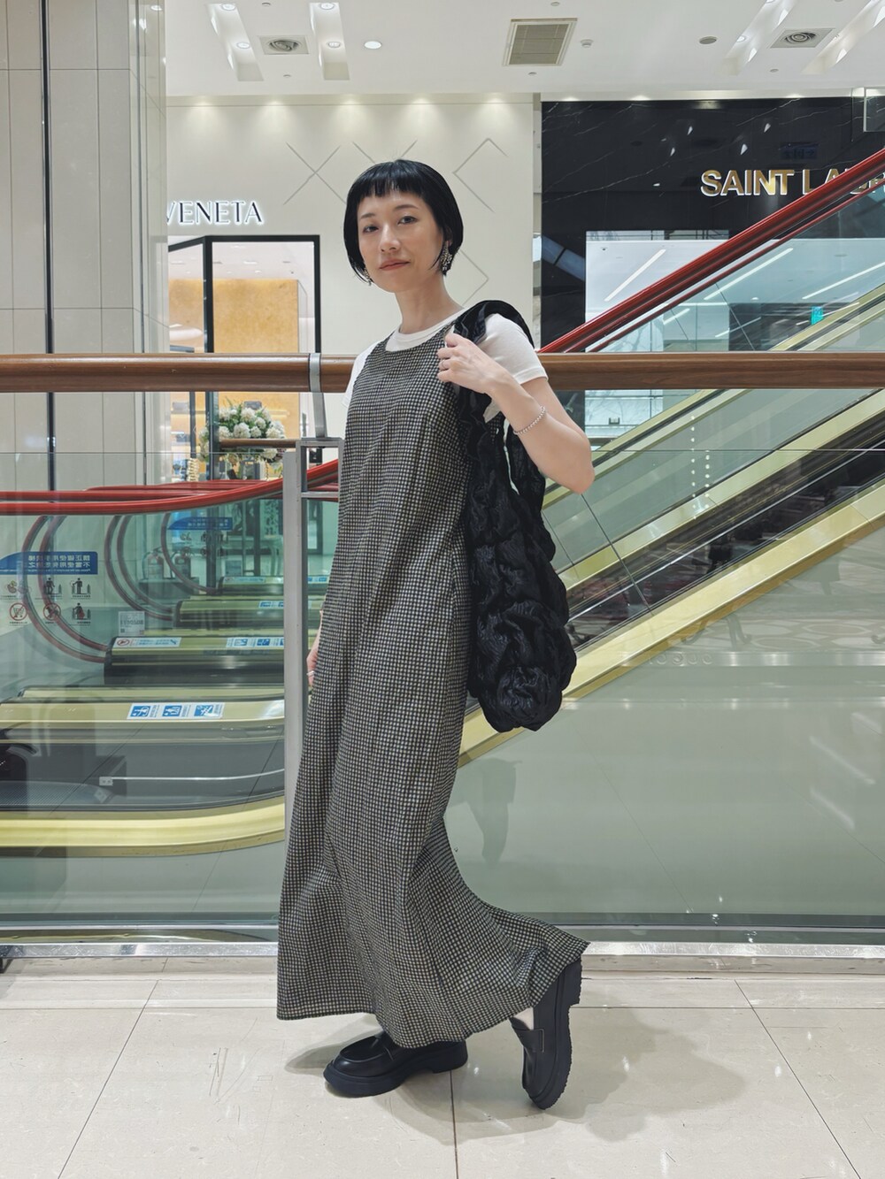 ブラック系のトートバッグ、ベージュ系のワンピース、シルバー系のピアス（両耳用）を着用したレディースの秋コーディネートの2枚目の写真