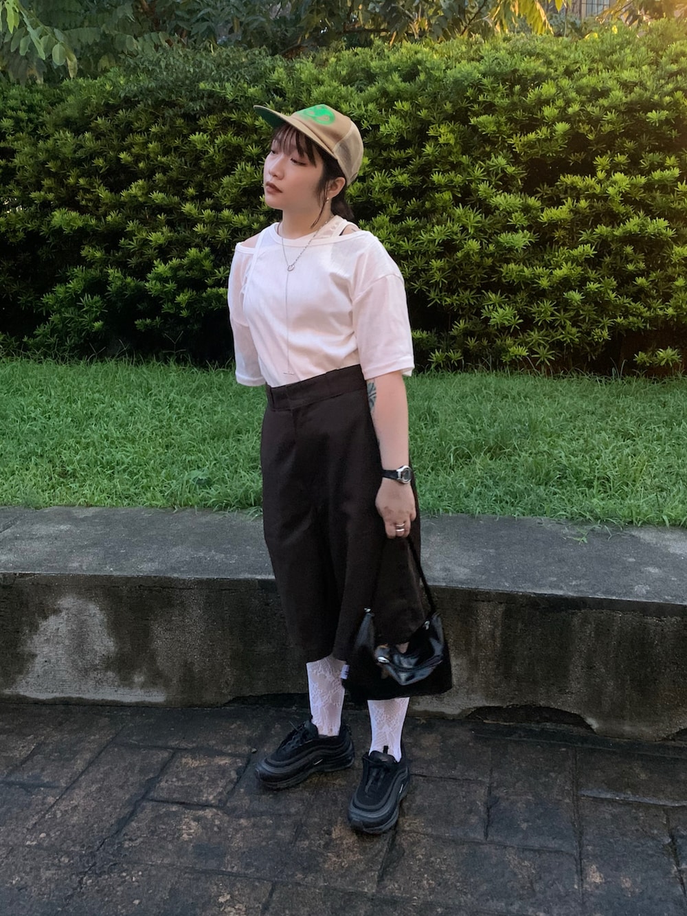 ホワイト系のチノパンツ、ブラック系のハンドバッグ、ブラック系のスニーカーを着用したレディースの夏コーディネートの2枚目の写真