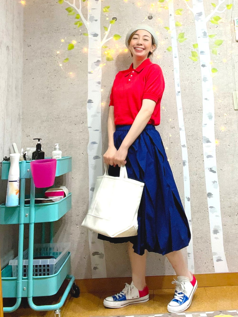 ホワイト系のトートバッグ、レッド系のポロシャツ、ブルー系のスカートを着用したレディースの夏コーディネートの3枚目の写真