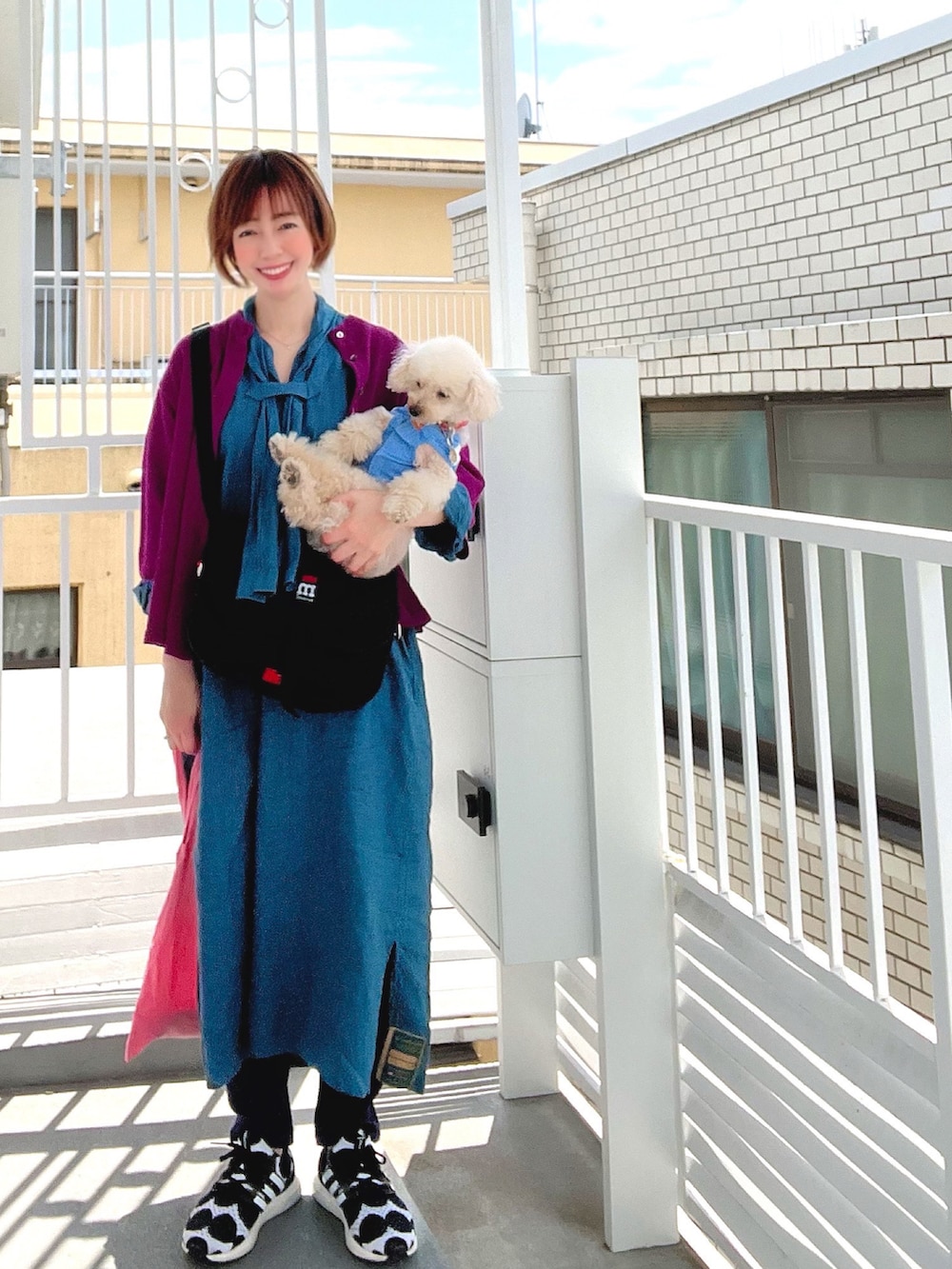 ブルー系のシャツワンピース、ブラック系のショルダーバッグ、ブラック系のスニーカーを着用したレディースの春コーディネートの4枚目の写真