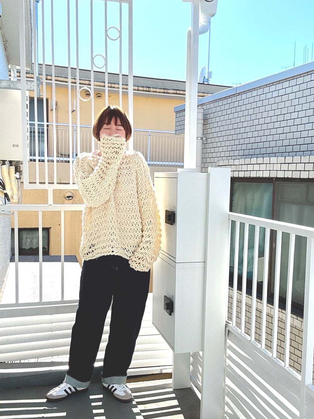 ホワイト系のニット/セーター、ブルー系のデニムパンツ、ホワイト系のスニーカーを着用したレディースの冬コーディネートの2枚目の写真